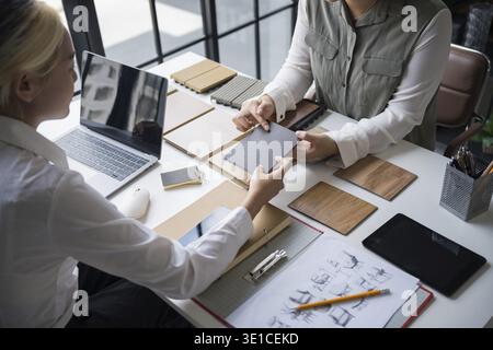 Designer di interni che presenta campioni di materiali in legno ecocompatibili per un arredamento sostenibile Foto Stock