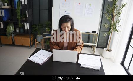 Maturo business asiatico donna imprenditrice in ufficio che utilizza laptop. donna d'affari degli anni '60 con donna anziana asiatica di tecnologia Foto Stock
