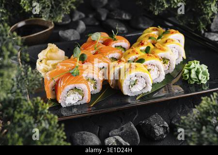 Panini di sushi con salmone e pesce in pastella serviti su un piatto nero Foto Stock