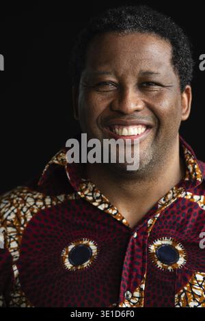 Ritratto di bell'uomo africano sorridente su sfondo nero Foto Stock