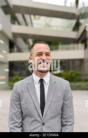 Ritratto di un uomo d'affari ispanico con la barba calva che indossa un abito nelle strade della città all'aperto Foto Stock