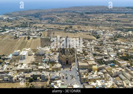 Vista aerea del villaggio di Xewkija con la Rotonda della Chiesa di San Giovanni Battista e la sua grande cupola che domina lo skyline di Gozo, Malta. Foto Stock