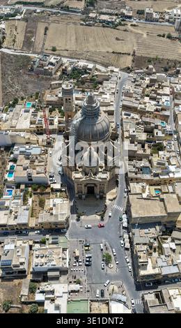 Veduta aerea della Rotonda della Chiesa di San Giovanni Battista a Xewkija, Gozo, con la grande cupola e il paesaggio urbano e i campi calcarei circostanti. Foto Stock