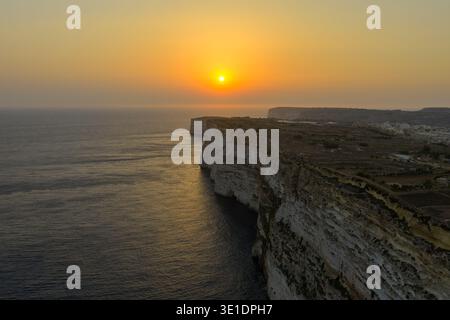 Tramonto sul Mar Mediterraneo visto dal bordo roccioso calcareo di Ta' Cenc (scogliere di Cenc) vicino a Sannat, Gozo, Malta. Foto Stock