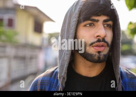 Ritratto di un giovane e bello uomo hipster indiano barbuto nelle strade all'aperto Foto Stock