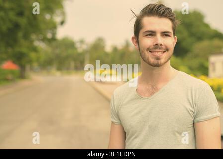 Ritratto di un giovane e bello uomo barbuto che si rilassa al parco Foto Stock
