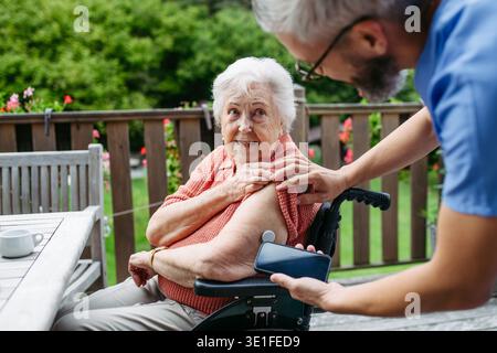 Infermiera domiciliare che controlla il livello di glucosio della donna anziana con smartphone. Foto Stock