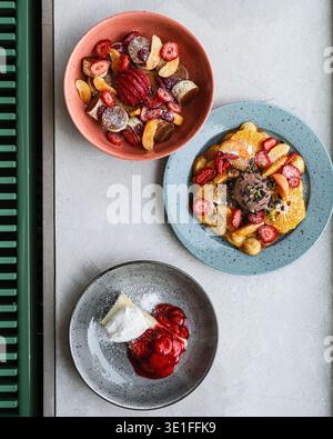 Ciotole luminose con Granola alla frutta e yogurt. Colorate ciotole per colazione con frutta di stagione e Granola Foto Stock
