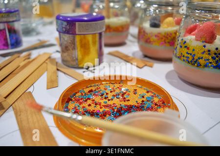 il posto di lavoro è la tavola del maestro della produzione di candele profumate con decorazioni e paillettes. Foto di alta qualità Foto Stock