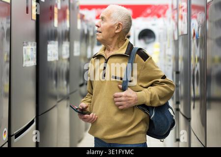 senor uomo pensionato acquistare frigorifero in showroom di elettrodomestici negozio Foto Stock