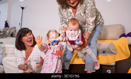 Famiglia felice e multigenerazionale che si diverte a dipingere insieme a casa Foto Stock