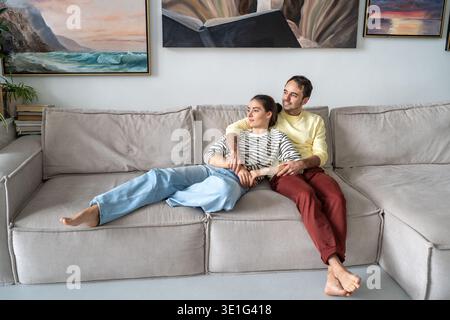Un uomo e una donna di coppia felici e premurosi che si rilassano a casa sul divano e si divertono insieme. Foto Stock