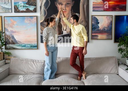 Allegra coppia sposata posa davanti al muro con dipinti che mostrano alta fiamma e sorridendo. Foto Stock