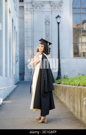 Berkeley Graduate Looking Back con Gown Over Shoulder Foto Stock