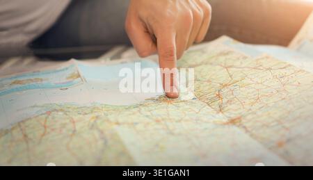 Primo piano che mostra il dito di un uomo su una mappa cartacea Foto Stock