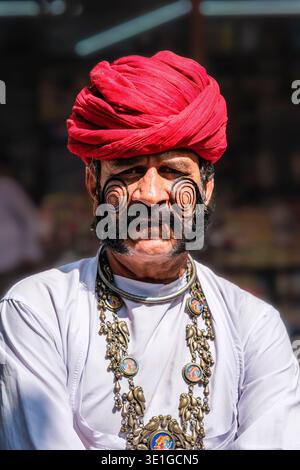A Jodhpur, un uomo con baffi e barba ricurvi tradizionali indossa un vibrante turbante rosso e tradizionali gioielli cerimoniali. Foto Stock