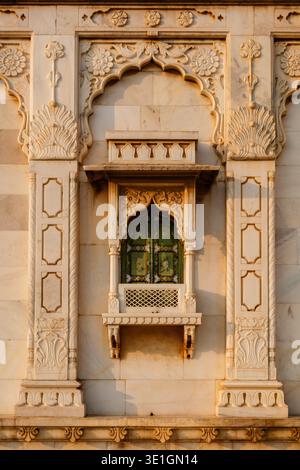 Un primo piano di una finestra decorativa in marmo con persiane di legno verdi sulla parete esterna del cenotafio Jaswant Thada a Jodhpur. Foto Stock