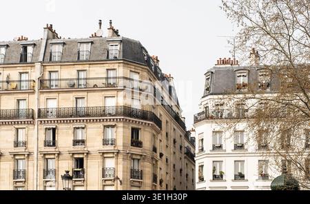 Edifici residenziali parigini classici con eleganti balconi e tetti in mansarda. L'architettura europea senza tempo è stata catturata in una tranquilla strada cittadina a par Foto Stock