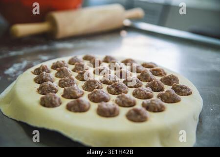 Primo piano di un tavolo con impasto crudo, su cui sono disposte piccole palline di carne macinata, pronte per cucinare gnocchi. Dispositivo per una rapida produzione di gnocchi Foto Stock