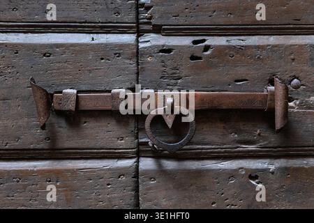 Lucchetto in metallo antico ruggine con anello a forma di cuore montato su una porta in legno resistente agli agenti atmosferici che cattura i dettagli dell'antica architettura rustica del Canale di Tenno Trent Foto Stock