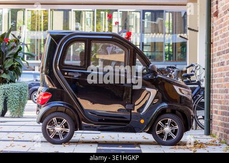 Microauto elettrica parcheggiata in centro città Foto Stock