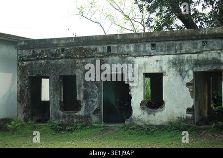 Vecchio edificio abbandonato con pareti danneggiate e finestre rotte in un ambiente rurale all'aperto in Bangladesh Foto Stock