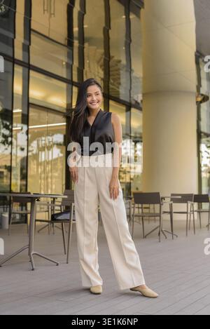 Ritratto a tutta lunghezza di bella donna asiatica all'aperto al bar ristorante foto verticale Foto Stock