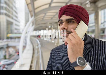 Ritratto di giovane bello indiano imprenditore Sikh indossando turbante mentre esplorate la città di Bangkok, Thailandia Foto Stock