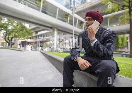 Ritratto di giovane bello indiano imprenditore Sikh indossando turbante mentre esplorate la città di Bangkok, Thailandia Foto Stock