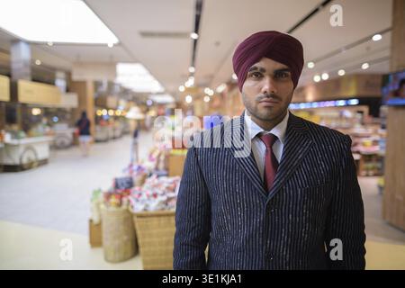 Ritratto di giovane bello indiano imprenditore Sikh indossando turbante mentre esplorate la città di Bangkok, Thailandia Foto Stock