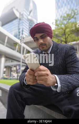 Ritratto di giovane bello indiano imprenditore Sikh indossando turbante mentre esplorate la città di Bangkok, Thailandia Foto Stock