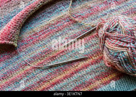 Confortevole scena di lavorazione a maglia fatta a mano con palline colorate in filato di lana e aghi in legno. Foto di alta qualità Foto Stock