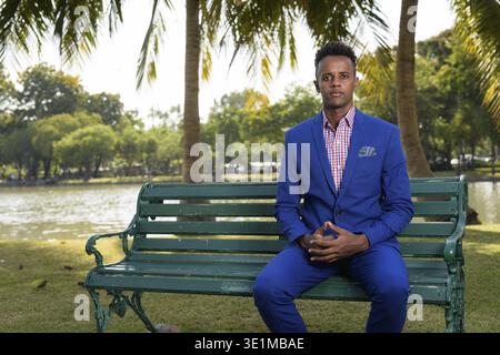 Ritratto di giovane bello imprenditore africano tuta da indossare durante i momenti di relax presso il parco a Bangkok, in Thailandia Foto Stock
