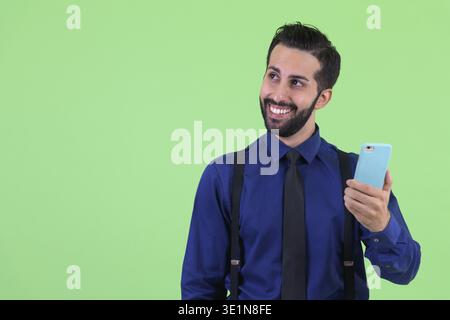 Foto in studio di un giovane e bellissimo uomo d'affari persiano barbato su sfondo verde Foto Stock