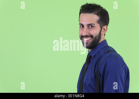 Foto in studio di un giovane e bellissimo uomo d'affari persiano barbato su sfondo verde Foto Stock
