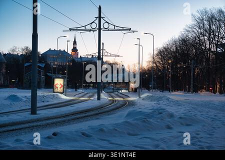 Tramonto invernale a Tallinn - piste del tram coperte di neve e skyline di Toompea Foto Stock