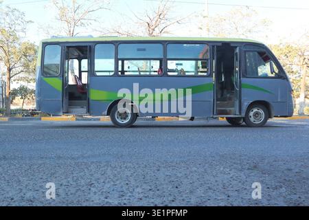 L'autobus cittadino a porte aperte si fermava lungo una strada soleggiata a Cartagena, Colombia, mostrando il sistema di trasporto pubblico Metrocars. Alberi e città Foto Stock