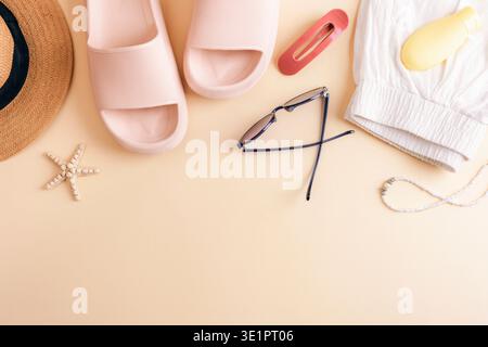 Accessori da spiaggia estivi con cappello, occhiali da sole, sandali, pantaloncini corti, clip per capelli, bottiglia di crema solare e stelle marine su sfondo giallo. Vista dall'alto, disposizione piatta Foto Stock