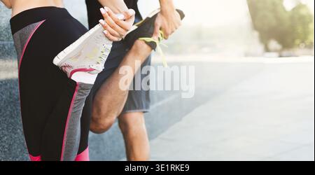 Coppia irriconoscibile che allunga le gambe prima di correre all'aperto in aree urbane Foto Stock