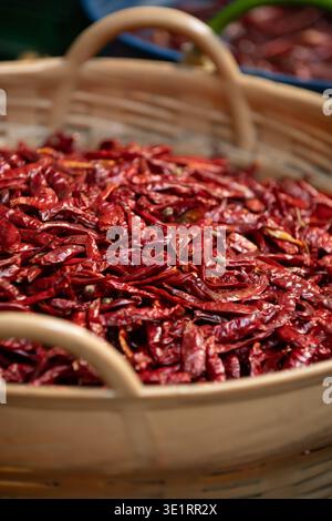 Primo piano di peperoncini rossi secchi in un cestello. Ingrediente alimentare piccante e fondo strutturato ideale per concetti culinari e alimentari. Foto Stock
