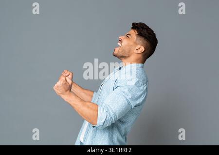 Ragazzo con rinserrata pugni urlando o ruggente rumorosamente, vista laterale Foto Stock