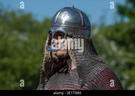 SHEVELEVO, RUSSIA - 18 LUGLIO 2025: Un giovane guerriero dell'alto Medioevo in un casco normanno e posta a catena in una giornata di sole. Epico festival della costa Foto Stock