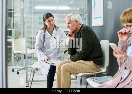 Donna Dottore consulenza uomo anziano in sala d'attesa medica Foto Stock
