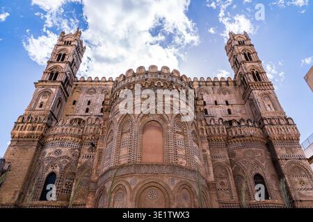 Vista dall'angolo basso delle maestose absidi della Cattedrale di Palermo. L'immagine evidenzia gli intricati intarsi di lava, gli archi interlacciati e le torri neogotiche cha Foto Stock