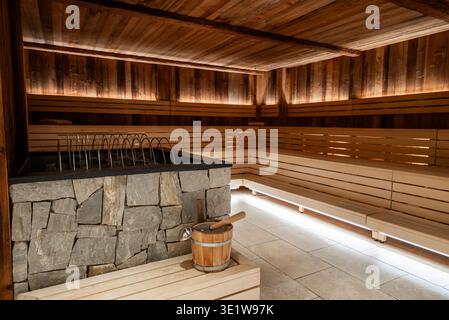 Sauna calda in legno con panche a gradini e riscaldamento rivestito in pietra Foto Stock