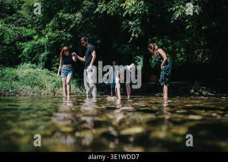 Il gruppo di amici e la famiglia si godranno insieme una giornata soleggiata lungo il fiume, esplorando le acque poco profonde. Foto Stock