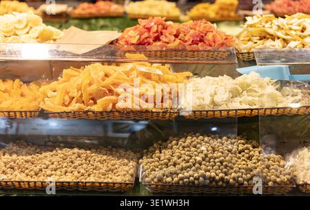 Un assortimento di frutta secca e noci è esposto in cesti di vimini in un mercato la selezione include mango papaya zenzero e arachidi rivestite tutto a. Foto Stock