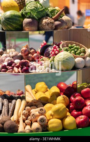 Una varietà di frutta e verdura fresche sono esposte su scaffali a gradini che mostrano un assortimento colorato di prodotti che illustrano il mangiare sano groce Foto Stock