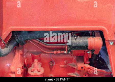 Un'immagine ravvicinata di un motore rosso di un trattore rivela i suoi componenti complessi, tra cui tubi, cablaggi e vari componenti meccanici per il settore agricolo automobilistico Foto Stock
