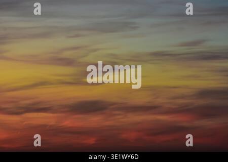 Un delicato cielo serale caratterizzato da un lavaggio viola pallido e delicate texture di nuvole rosa che ricordano un dipinto astratto ad acquerello al tramonto. Foto Stock